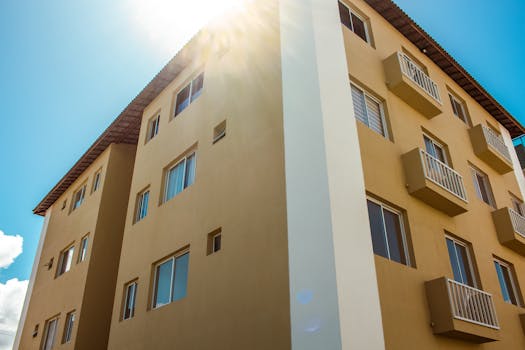 A newly constructed modern apartment building with balconies and windows under bright sunlight.