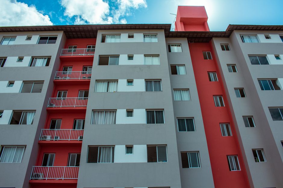 Un edificio residencial de gran altura con una impresionante fachada roja y balcones contra un cielo azul.