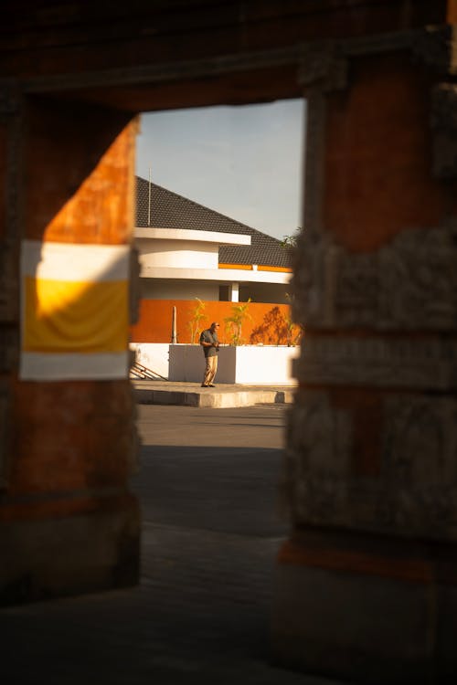 Man on the Sidewalk in Front of an Orange and White Building