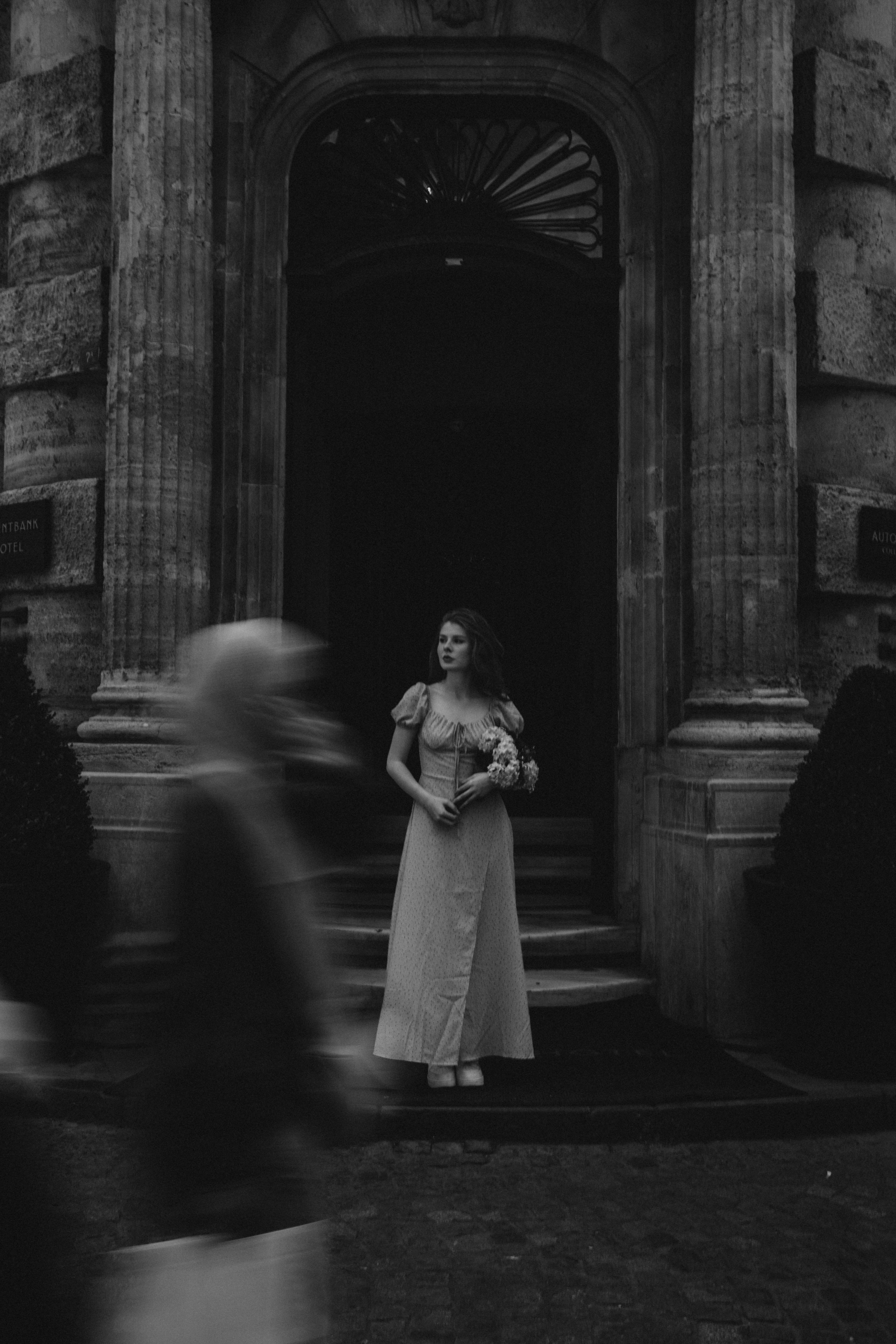 a woman in a wedding dress is standing outside a building