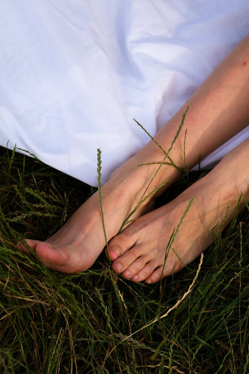 Bare Feet of a Woman Relaxing on a White Blanket