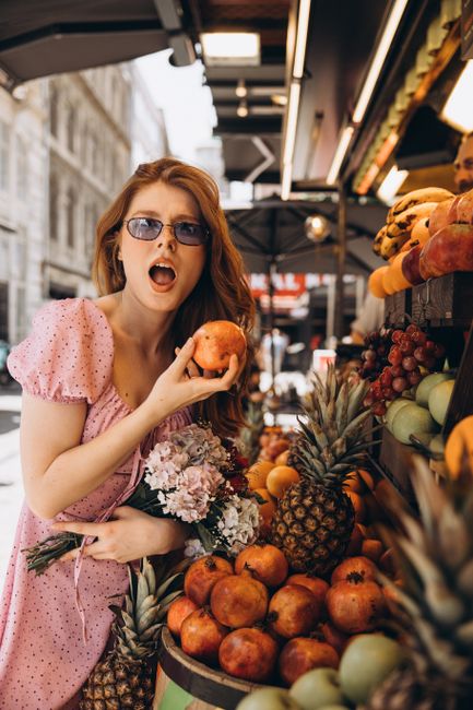 Stylish woman in pink dress shopping for fruits in a vibrant Istanbul market.