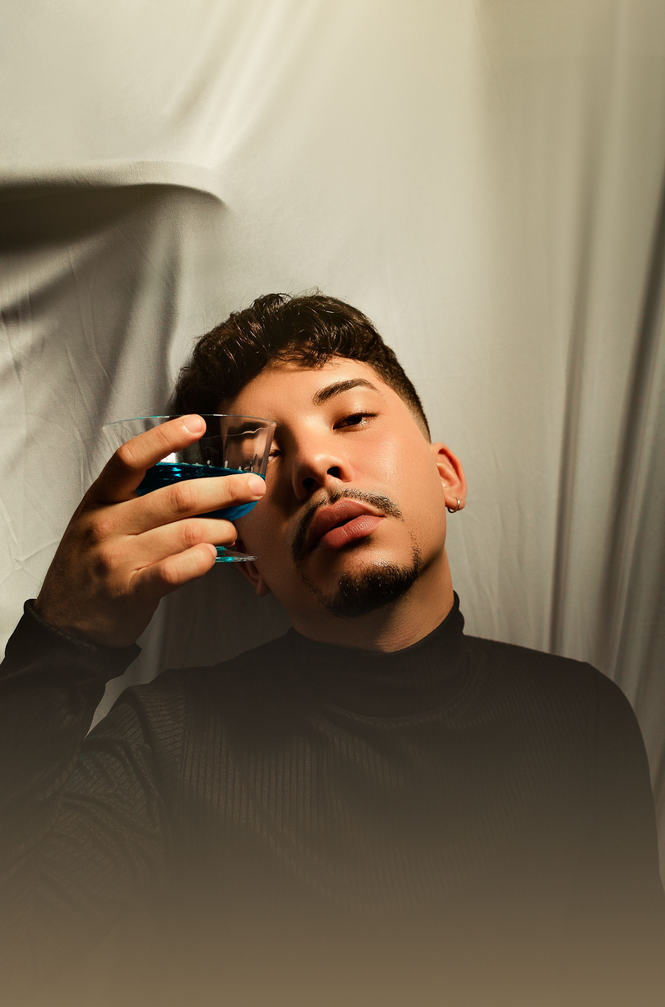 Artistic portrait of a man holding a glass with a dramatic lighting effect.
