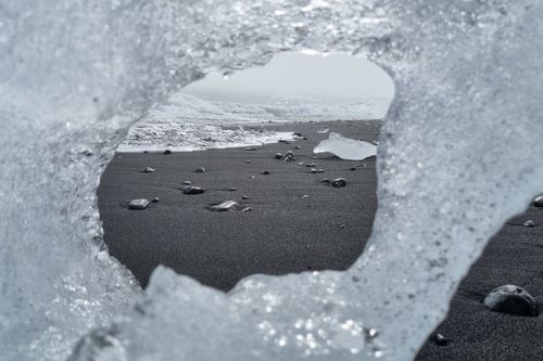 Free Ice formation frames a black sand beach, showcasing winter's icy beauty. Stock Photo