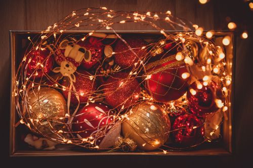 Free A box of vibrant Christmas ornaments wrapped in warm twinkling lights, perfect for holiday celebrations. Stock Photo