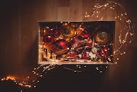 一个装满活力四射的圣诞装饰品和灯串的盒子，俯视着木制表面