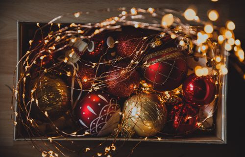 Free A box filled with festive Christmas ornaments and glowing string lights, perfect for holiday decor. Stock Photo