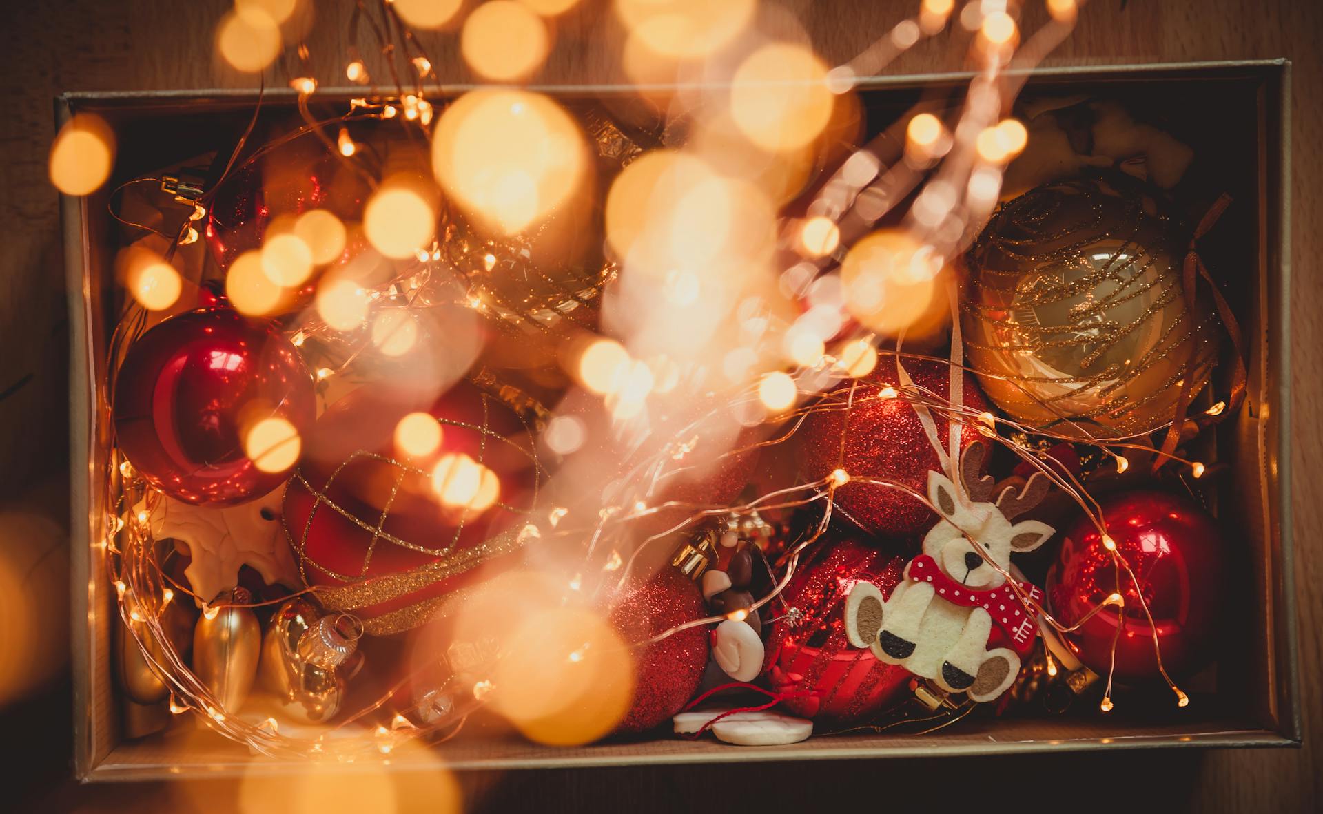 A cozy festive box filled with Christmas ornaments and string lights creating a warm holiday ambiance.