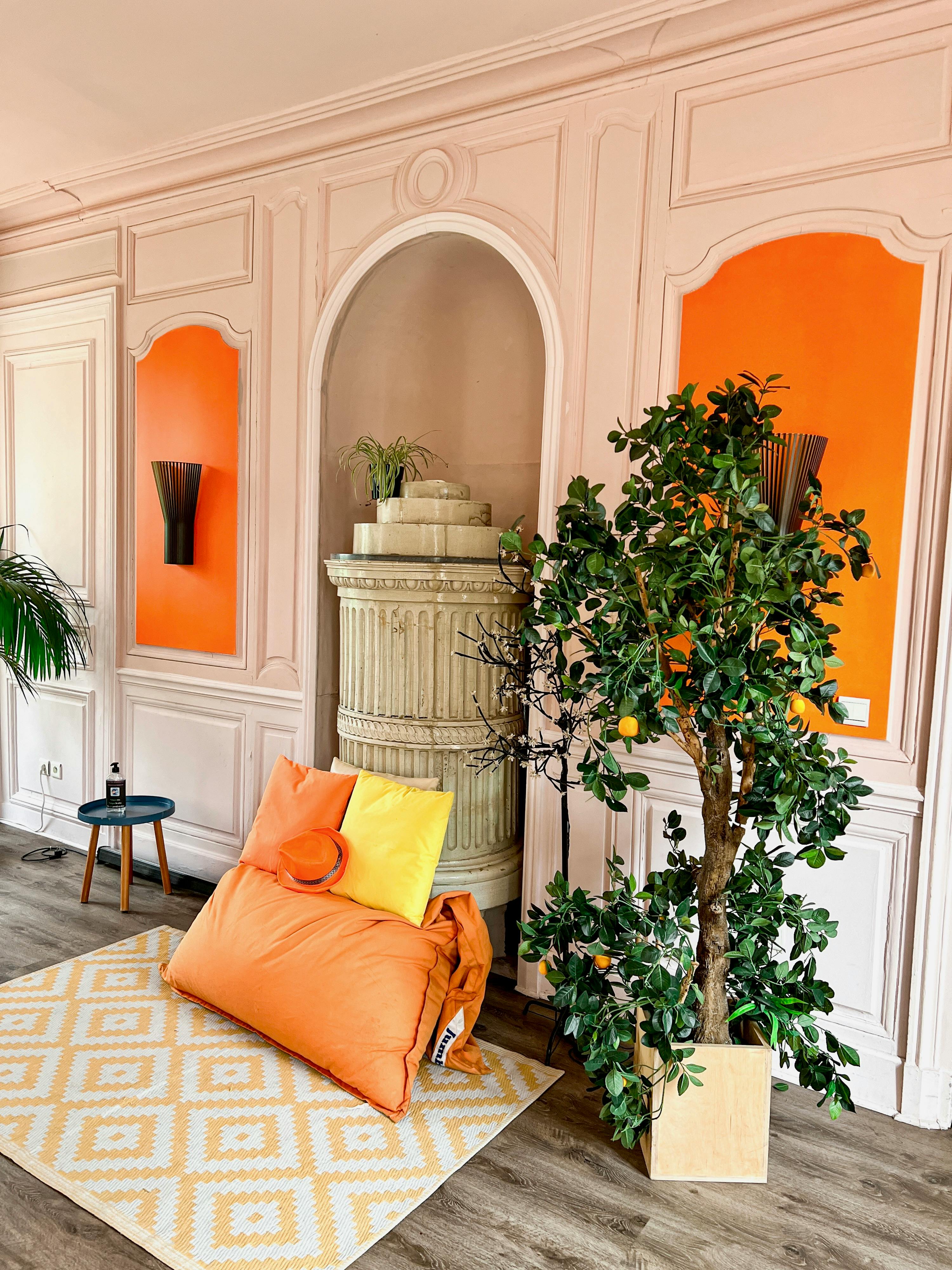 Stylish contemporary room featuring vibrant orange details, cushions, and a lush houseplant with elegant decor.