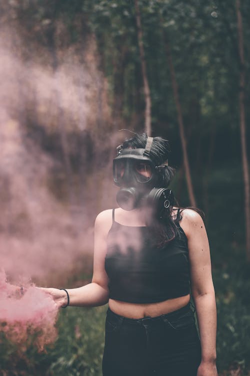 Woman in Gas Mask Holding Smoking Flare