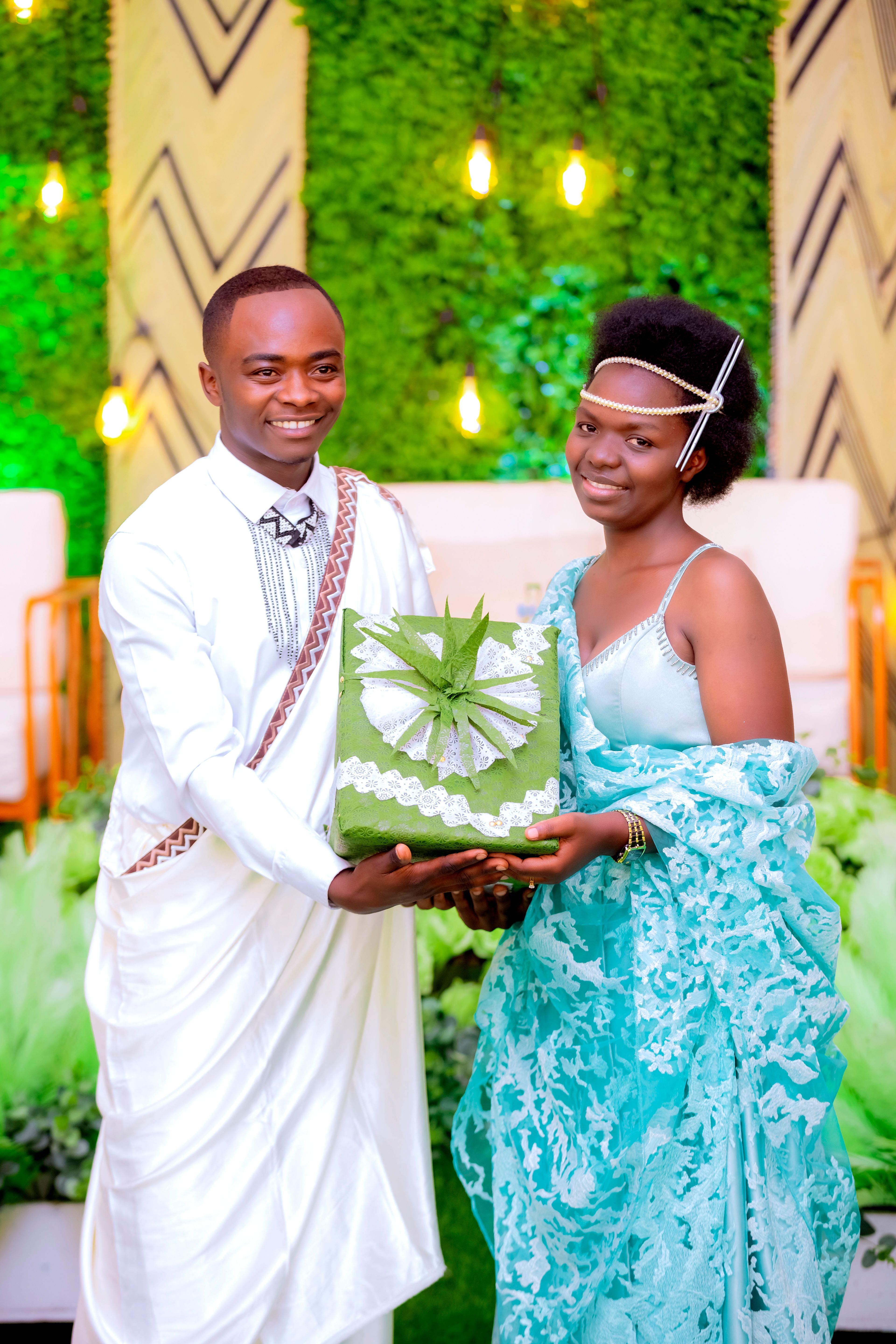 A couple in traditional attire exchanging a gift during a lively wedding celebration.