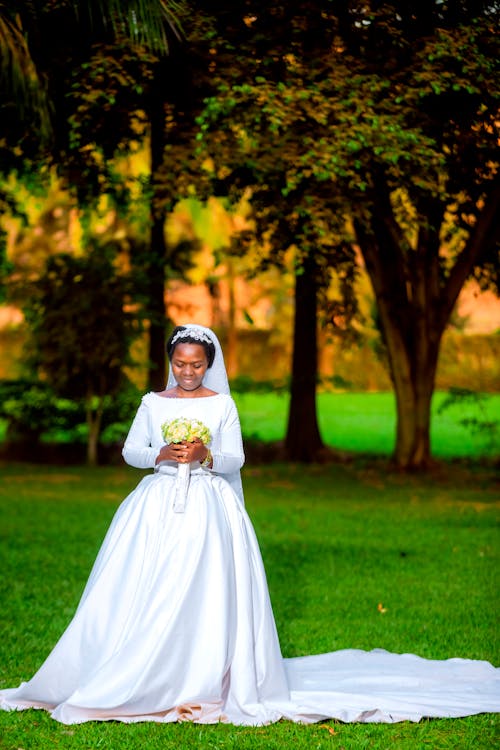 Bride Holding a Bouquet and Standing in a Park 