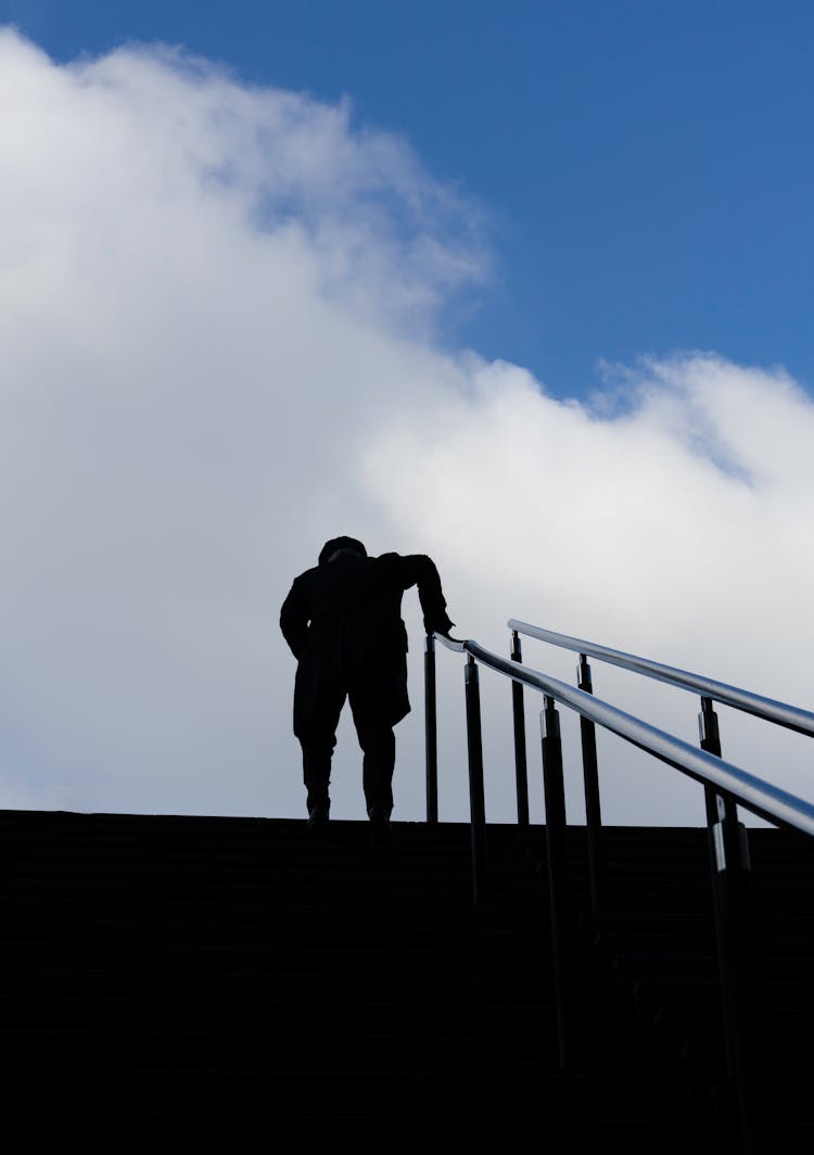 Silhouette Of Man Walking Upstairs Against Blue Sky