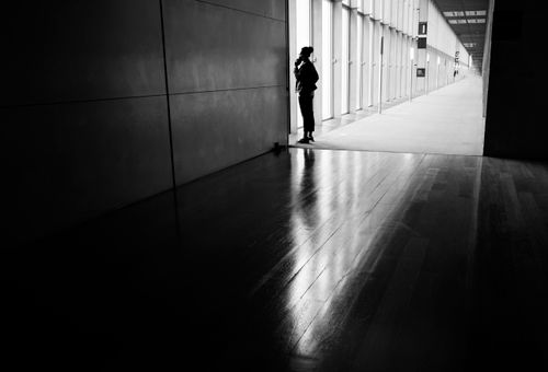 Free Silhouette of a woman standing in a modern corridor talking on the phone. Stock Photo