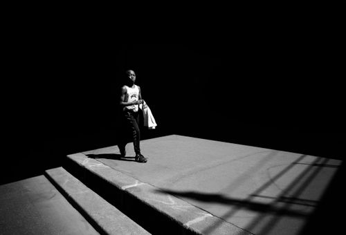 Free A man walking on a shadowy platform in a high contrast black and white scene. Stock Photo