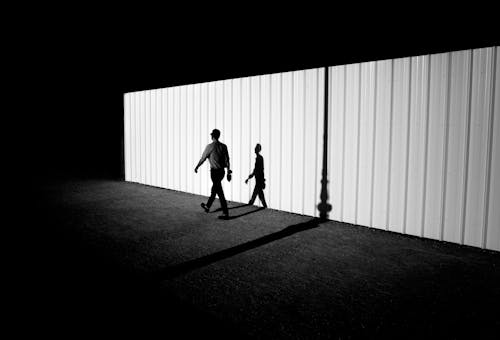 Man Walking near Wall in Black and White