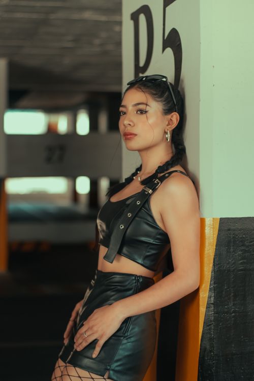 Free Fashionable young woman in black leather outfit posing in Cochabamba parking lot. Stock Photo