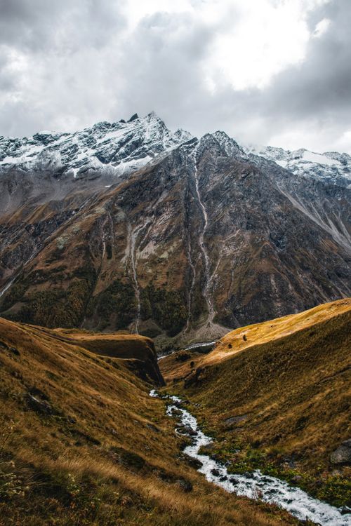 Free Breathtaking view of a snow-capped mountain and valley stream in Russia's natural landscape. Stock Photo