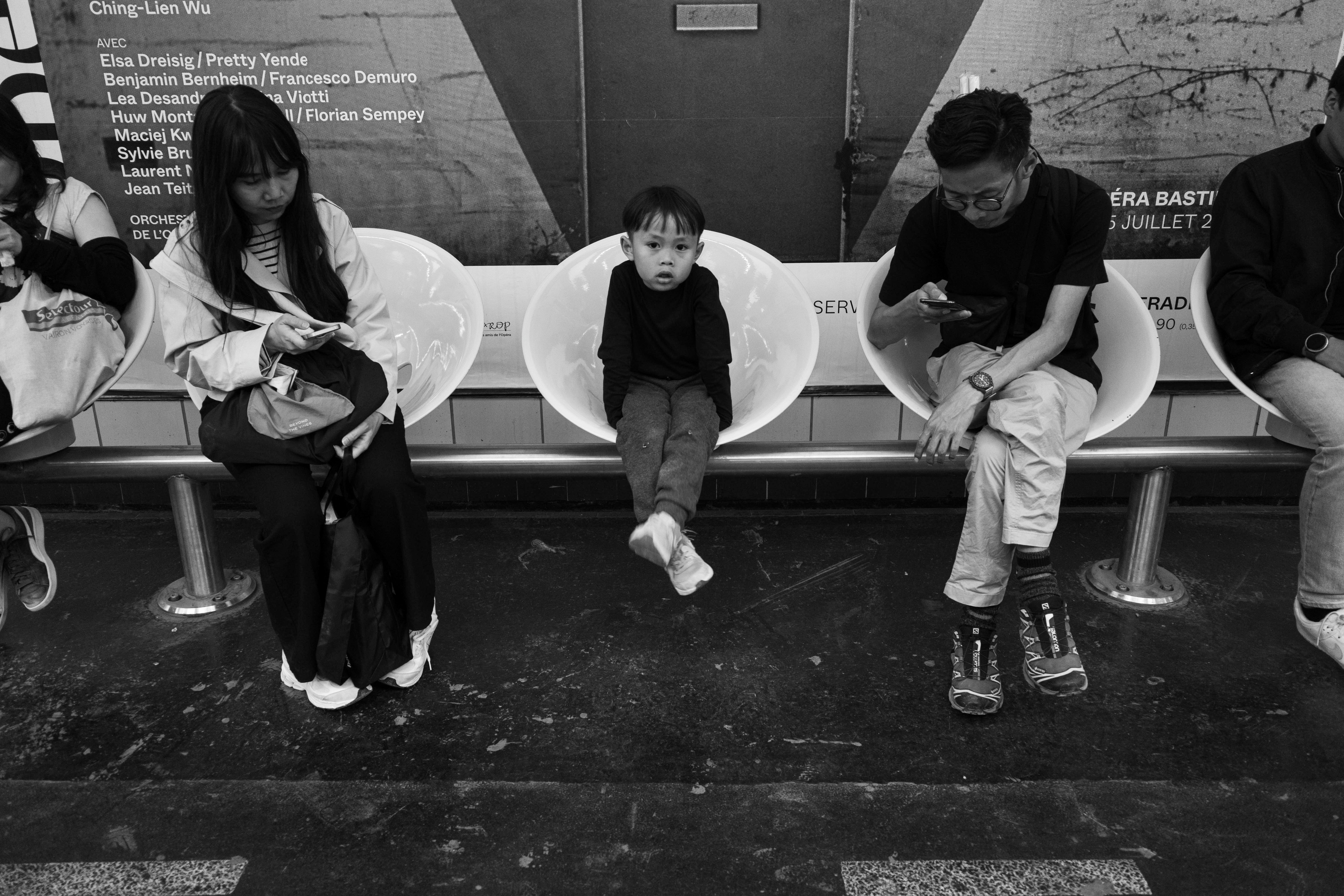Candid black and white photo of people waiting at a metro station, highlighting urban life.