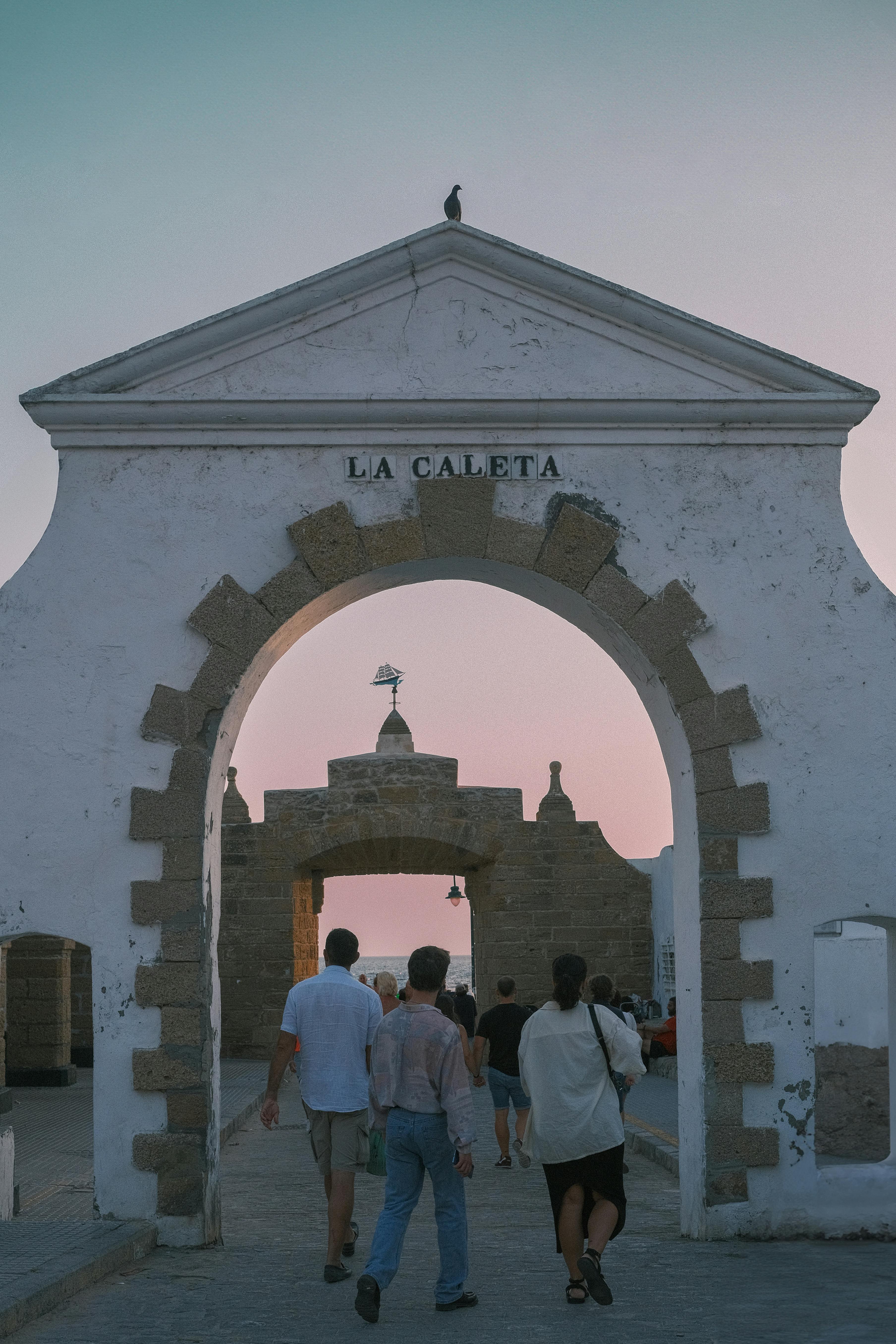 people walking through entrance of puerta de la caleta cadiz spain