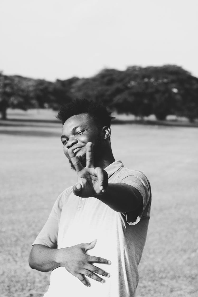 Smiling Young Man Showing Victory Hand Gesture