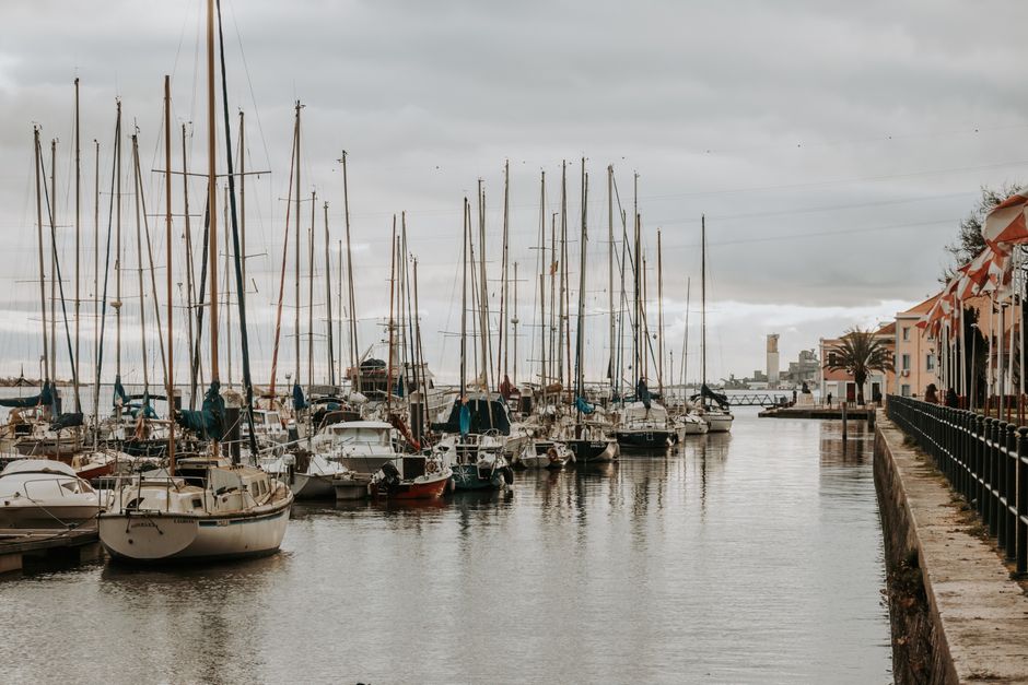 The lively waterfront scene at a Lisbon <span class="notranslate"><em>doca</em></span>, filled with diners and boats at sunset.