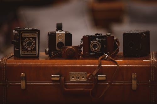 免費 棕色手提箱上的四個彩色照相機 圖庫相片