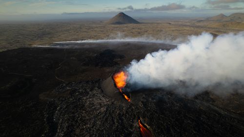 Free Dynamic aerial shot of an erupting volcano with lava and smoke, showcasing raw nature. Stock Photo