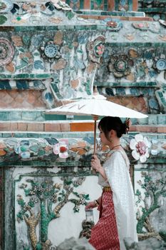Woman in traditional attire with umbrella at a cultural site.