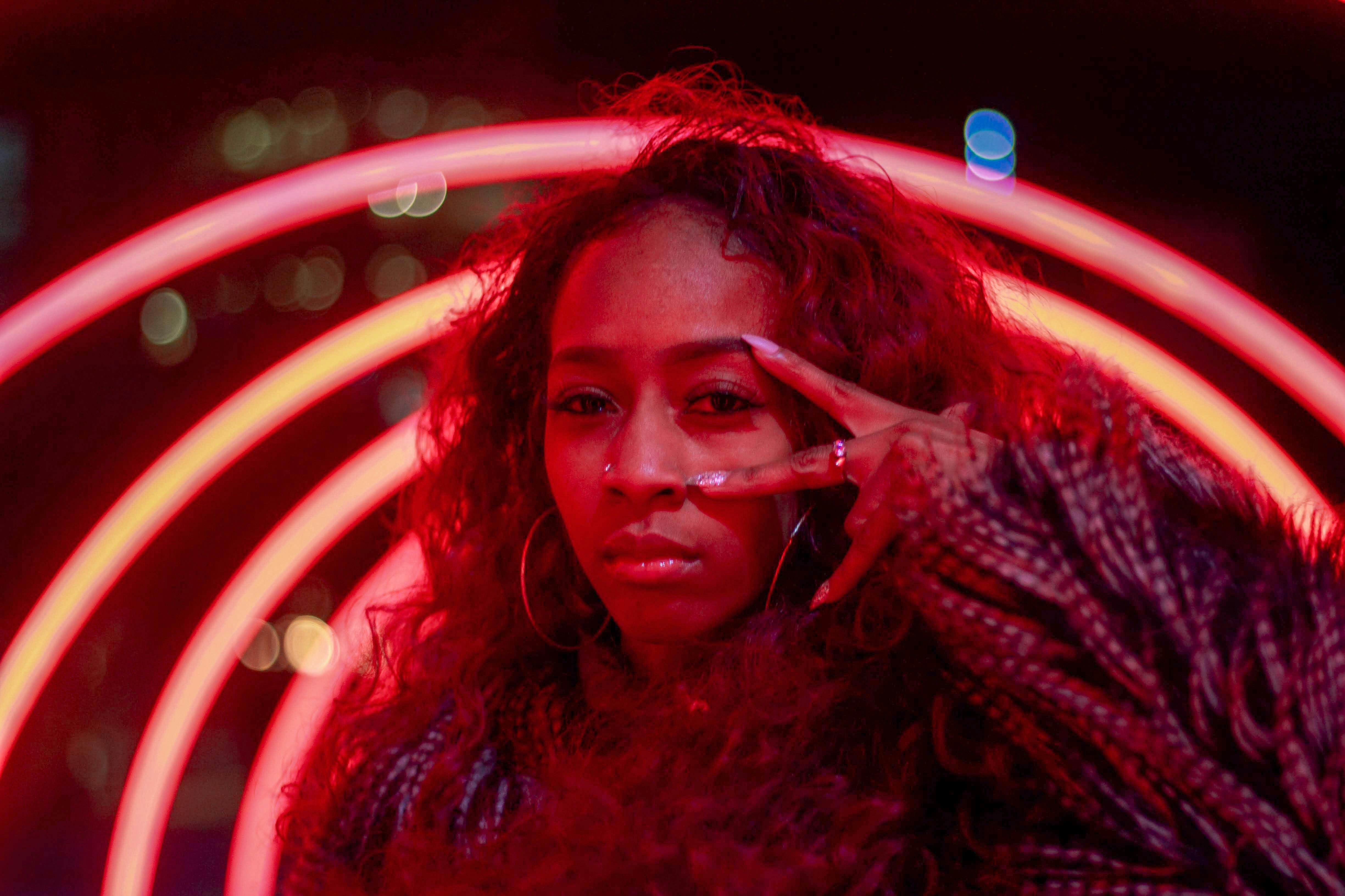 Female with curly hair posing under neon lights, creating a vibrant and artistic night portrait.