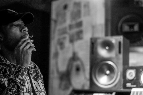 Free Stylish black and white image of a man wearing a cap smoking in a studio with speakers. Stock Photo