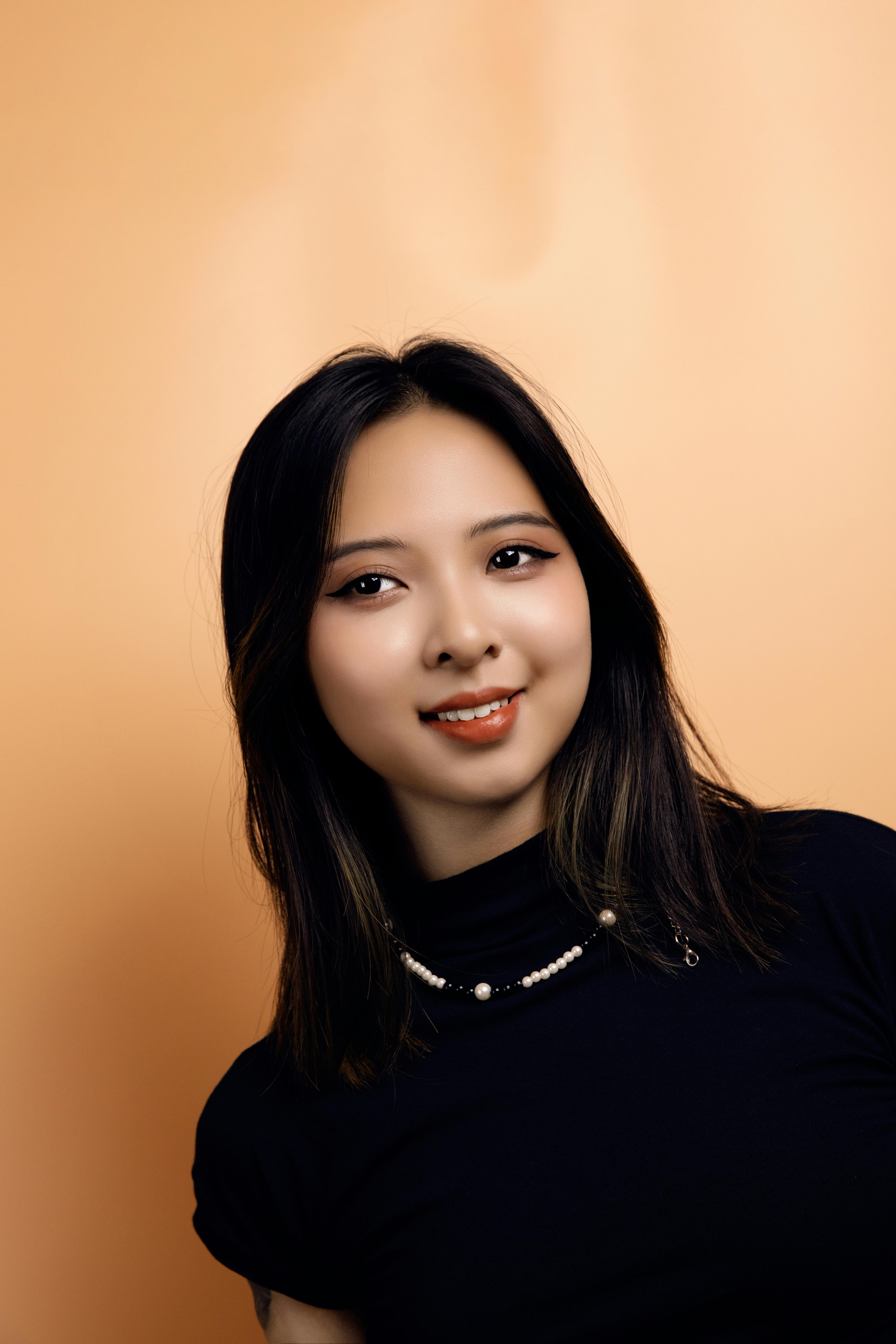 Charming portrait of a smiling East Asian woman in Hanoi with a yellow backdrop.