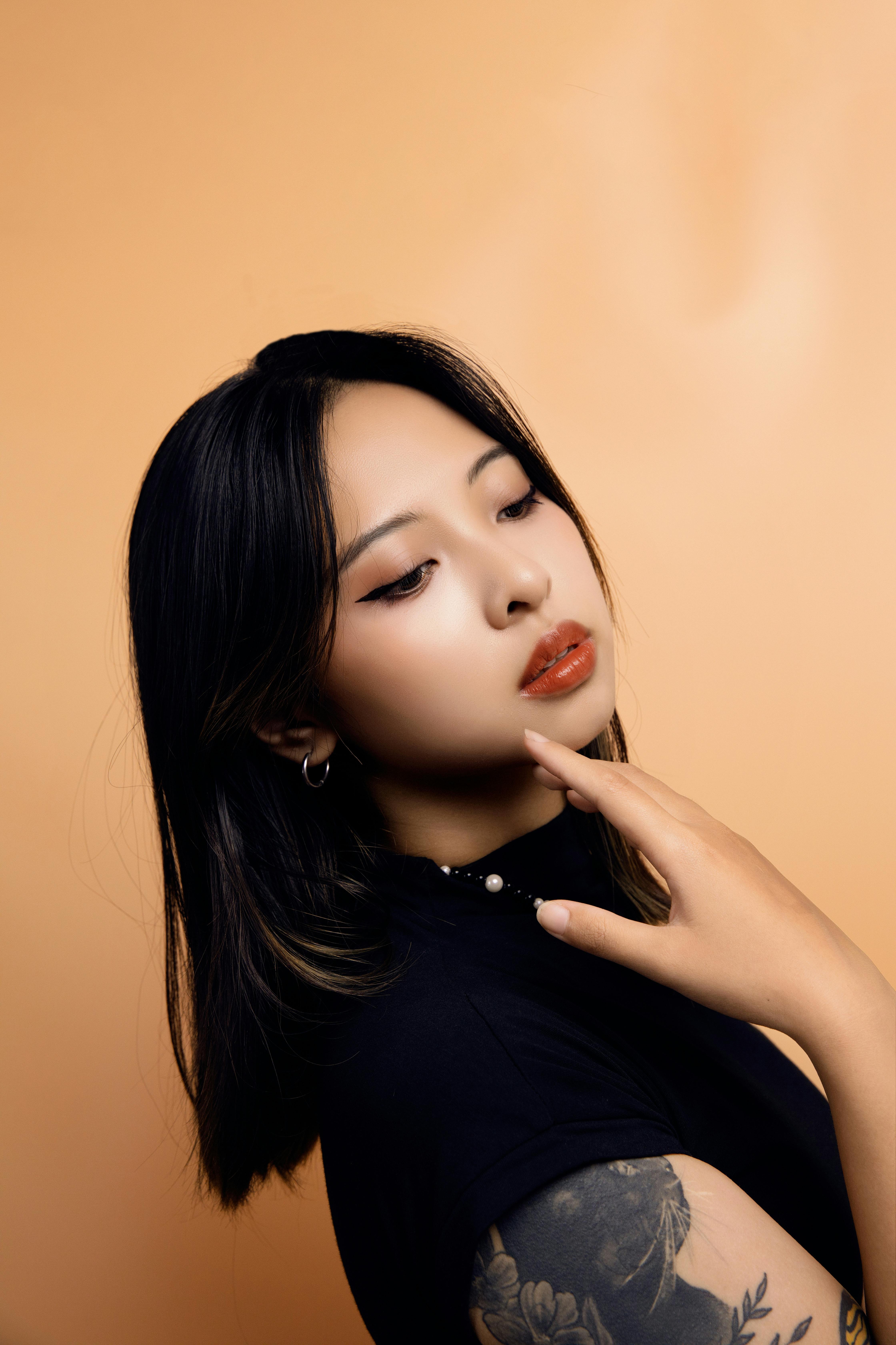 Young woman with tattoos posing gracefully in studio setting.
