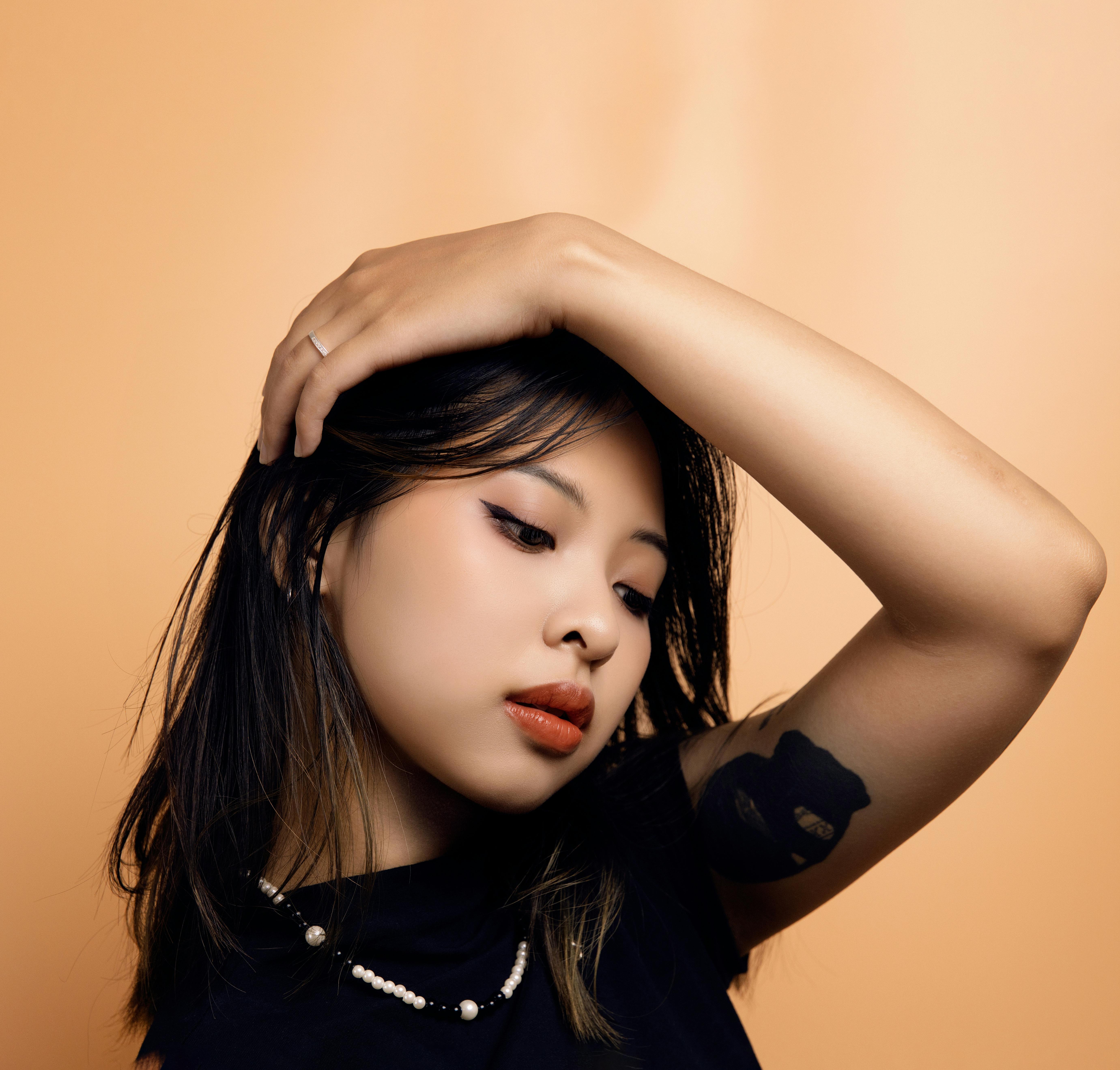Stylish studio portrait of a young Asian woman with a confident pose and chic fashion sense.