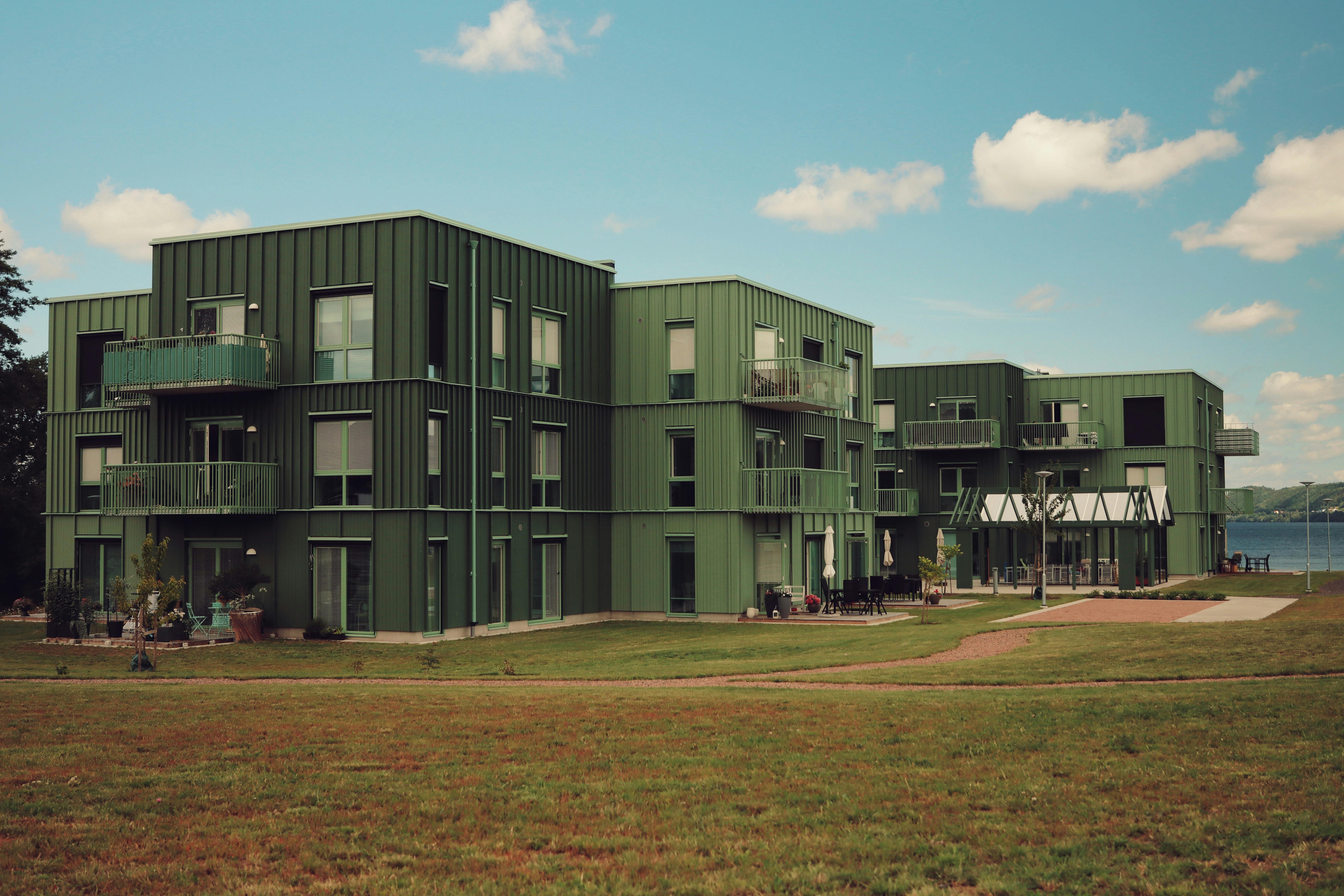 Stylish green apartments near a lake in Jönköping, Sweden, with a bright sky.