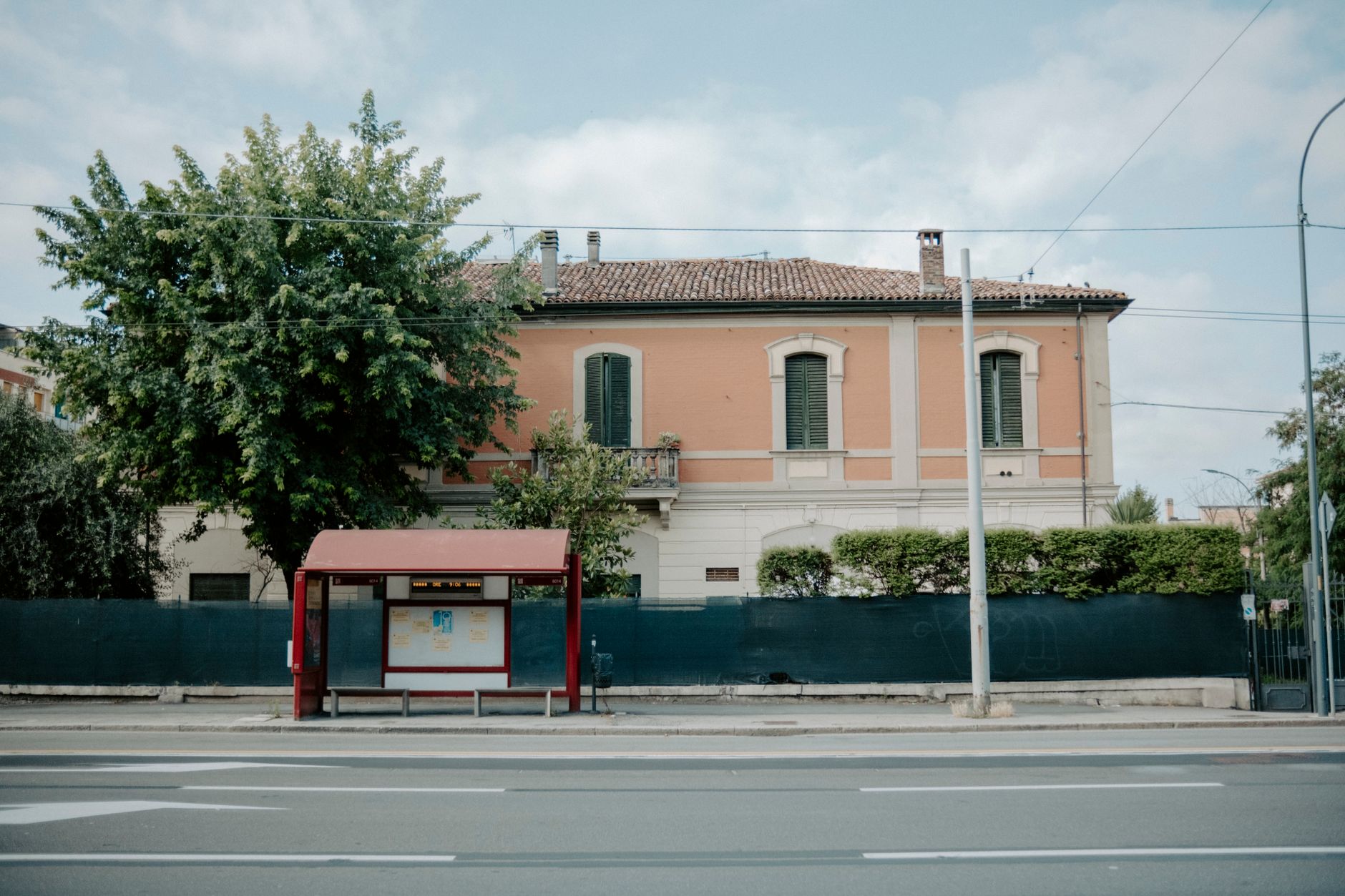 Una fermata autobus suburbana davanti a un edificio storico, utile per illustrare un punto di partenza o di cambio lungo il percorso.