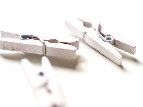 Closeup of white wooden clothespins with shadow on white background in bright light