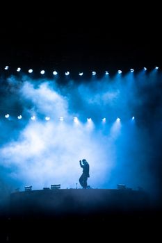 A captivating silhouette of a performer surrounded by blue lights on a smoky stage.