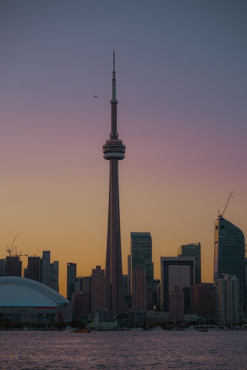 Free Toronto skyline featuring the CN Tower at sunset with vibrant cityscape reflections. Stock Photo