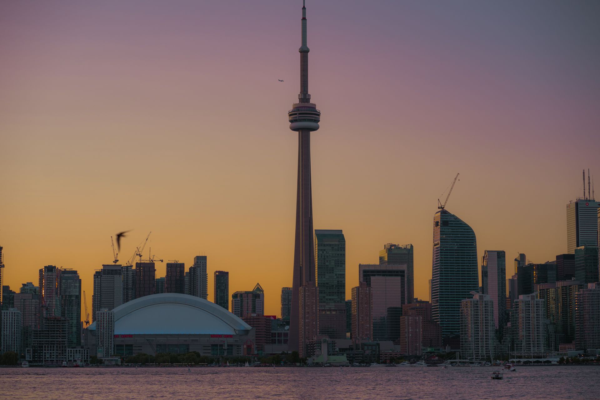 Beautiful Toronto skyline at sunset with the iconic CN Tower and reflections in the water.