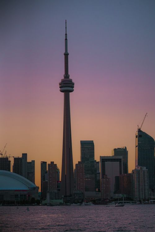 Free Vibrant Toronto skyline at sunset featuring the iconic CN Tower and waterfront reflections. Stock Photo