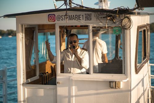 Free Boat captain uses microphone while navigating on a sunny day at the waterfront. Stock Photo