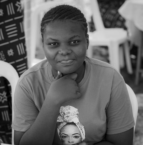 Free Black and white photo of a smiling woman in a patterned t-shirt, offering a natural and relaxed pose. Stock Photo