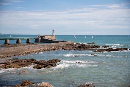 Rocks on Sea Shore with Lighthouse behind