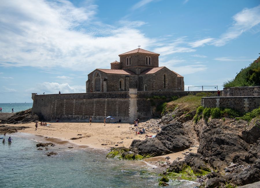 Scenic view of Prieure Saint-Nicolas church by the beach in France, under a blue sky.