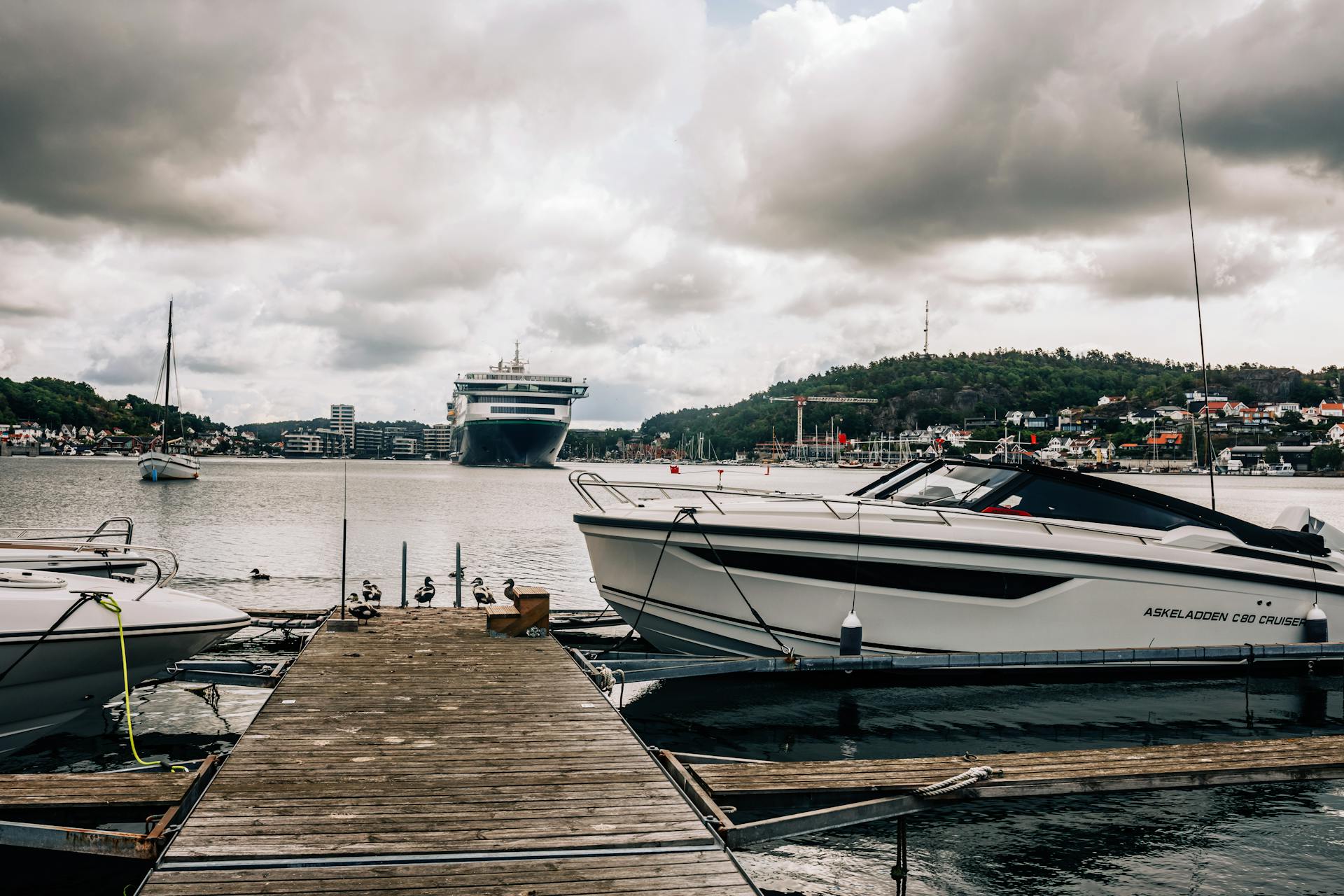 Vibrant marina in Sandefjord, Norway with boats and cruise ships under cloudy skies.