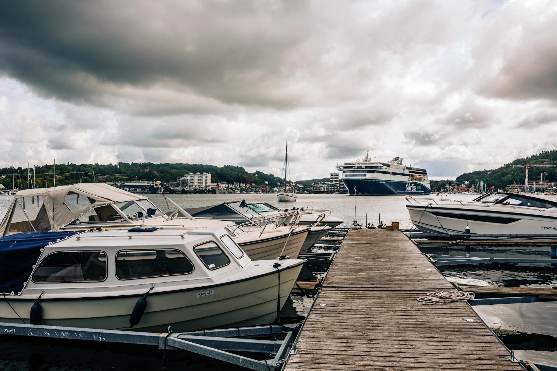 A tranquil view of Sandefjord harbor with boats and a cruise ship under dramatic clouds.
