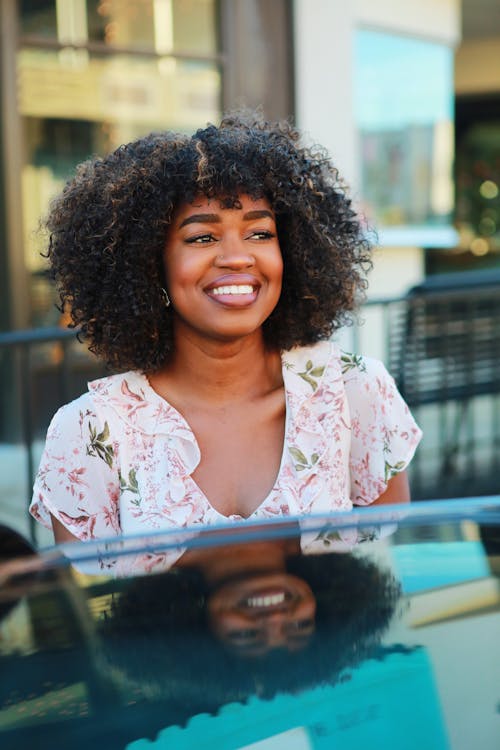 Фотография женщины, улыбающейся с отражением на автомобиле