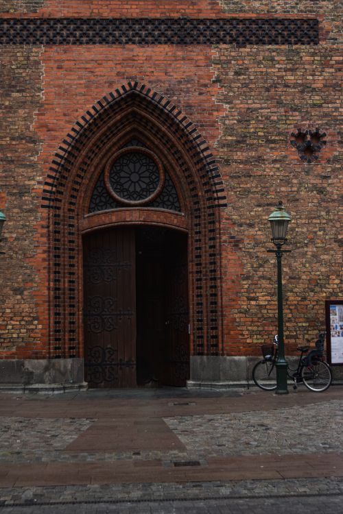 Free A vintage gothic arched door in a brick facade, embodying urban historical architecture. Stock Photo
