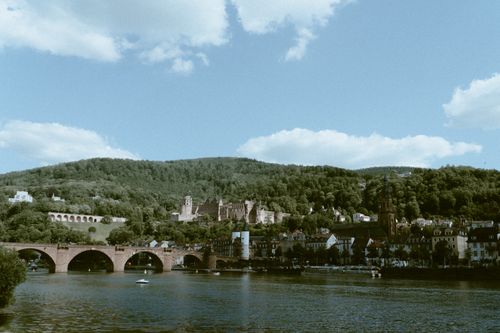 Free Picturesque view of the historic bridge and castle in Heidelberg, Germany, surrounded by lush hills and a river. Stock Photo